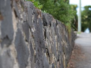 Close-up of a weathered stone retaining wall, showcasing potential material concerns linked to a leaning retaining wall.