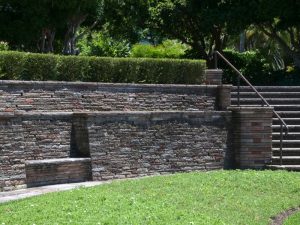 Stone retaining wall with steps and shrubs, highlighting potential issues causing a leaning retaining wall.